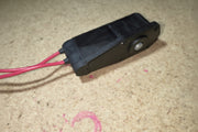 Black electronic device with red wires on a textured surface