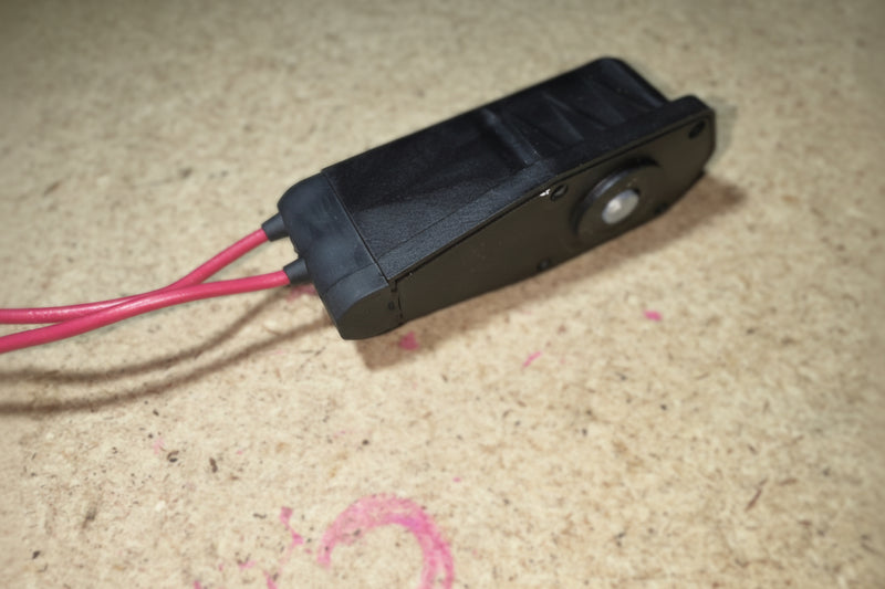 Black electronic device with red wires on a textured surface