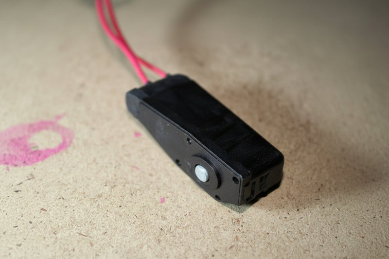 Black electronic component with wires on a beige surface