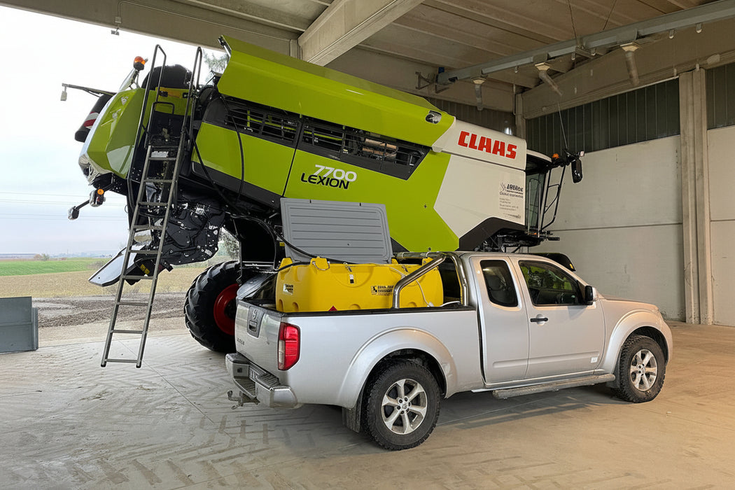 Large agricultural machine attached to a pickup truck inside a building
