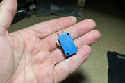 Small mechanical switch held in a hand on a dark surface