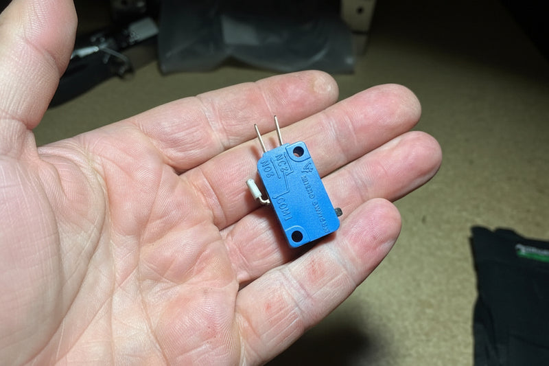 Small mechanical switch held in a hand on a dark surface