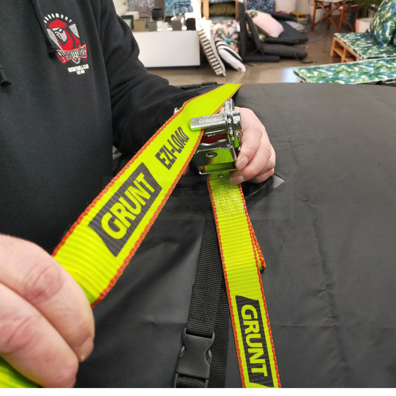 Person holding a yellow and black 'Grunt' strap in an indoor setting.