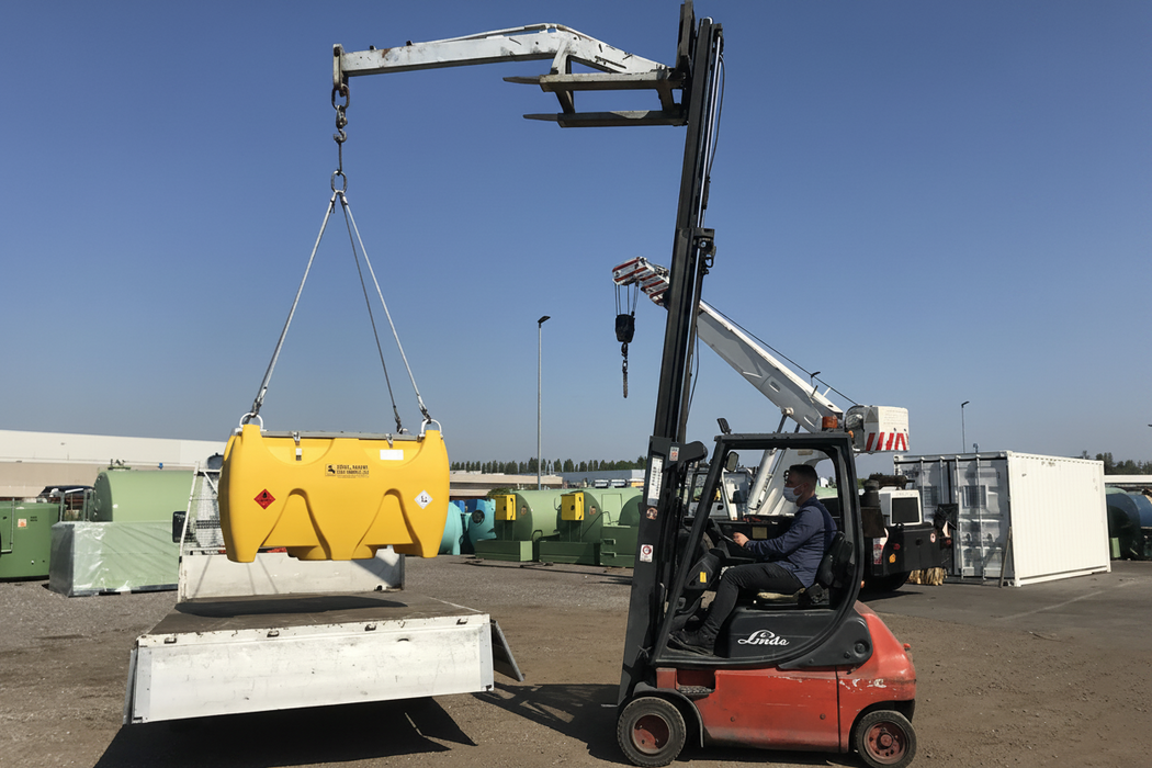 Forklift lifting a yellow container with a clear blue sky in the background