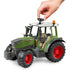 Toy model Fendt tractor with green body, red wheels, and grey accents on a white background