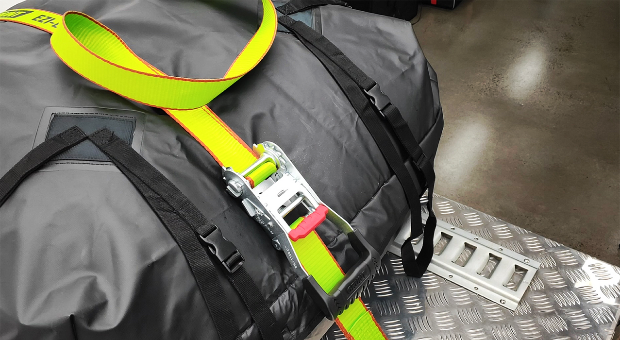 Close-up of a gray bag with a yellow strap and black buckle on a metallic surface.